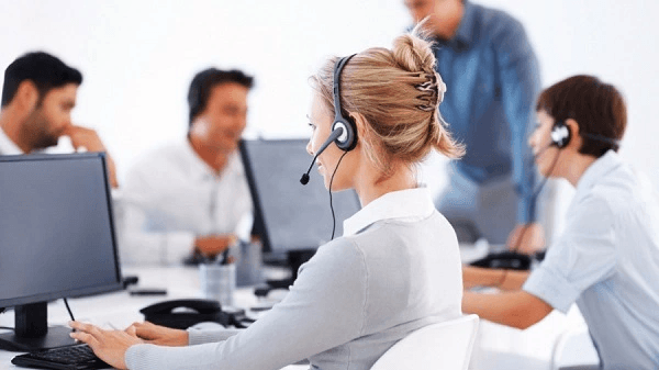 Nhân viên tổng đài đeo tai nghe làm việc trước máy tính